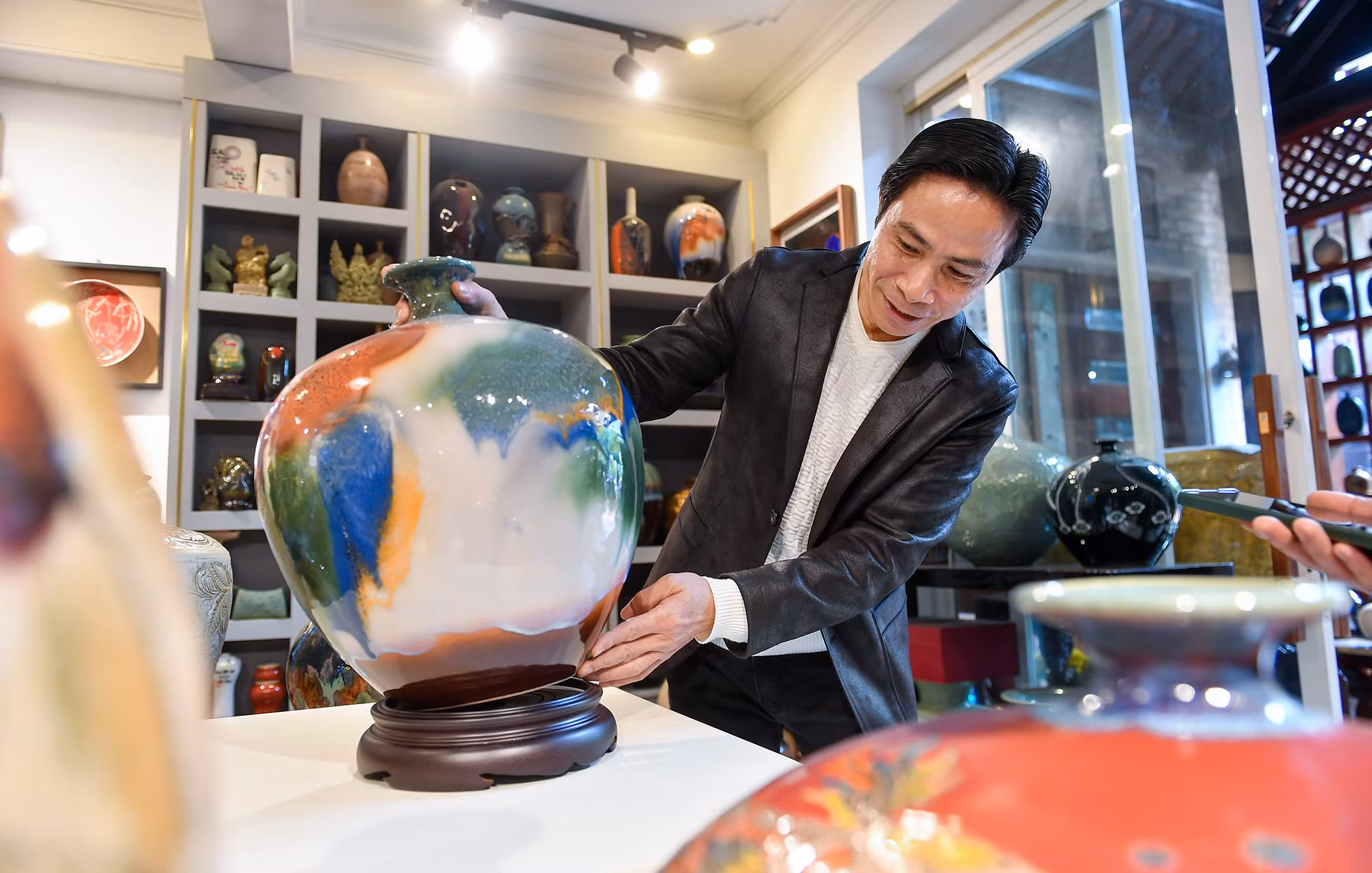 Nghệ nhân ưu tú Trần Đức Tân bên sản phẩm gốm dòng men Suối Ngọc.