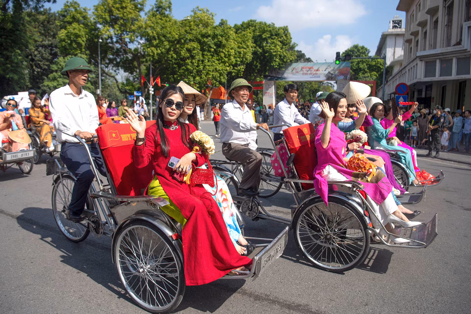 Đoàn diễu hành áo dài kết hợp cùng xích lô trang trí hoa di chuyển qua khu vực trước tượng đài Lý Thái Tổ.