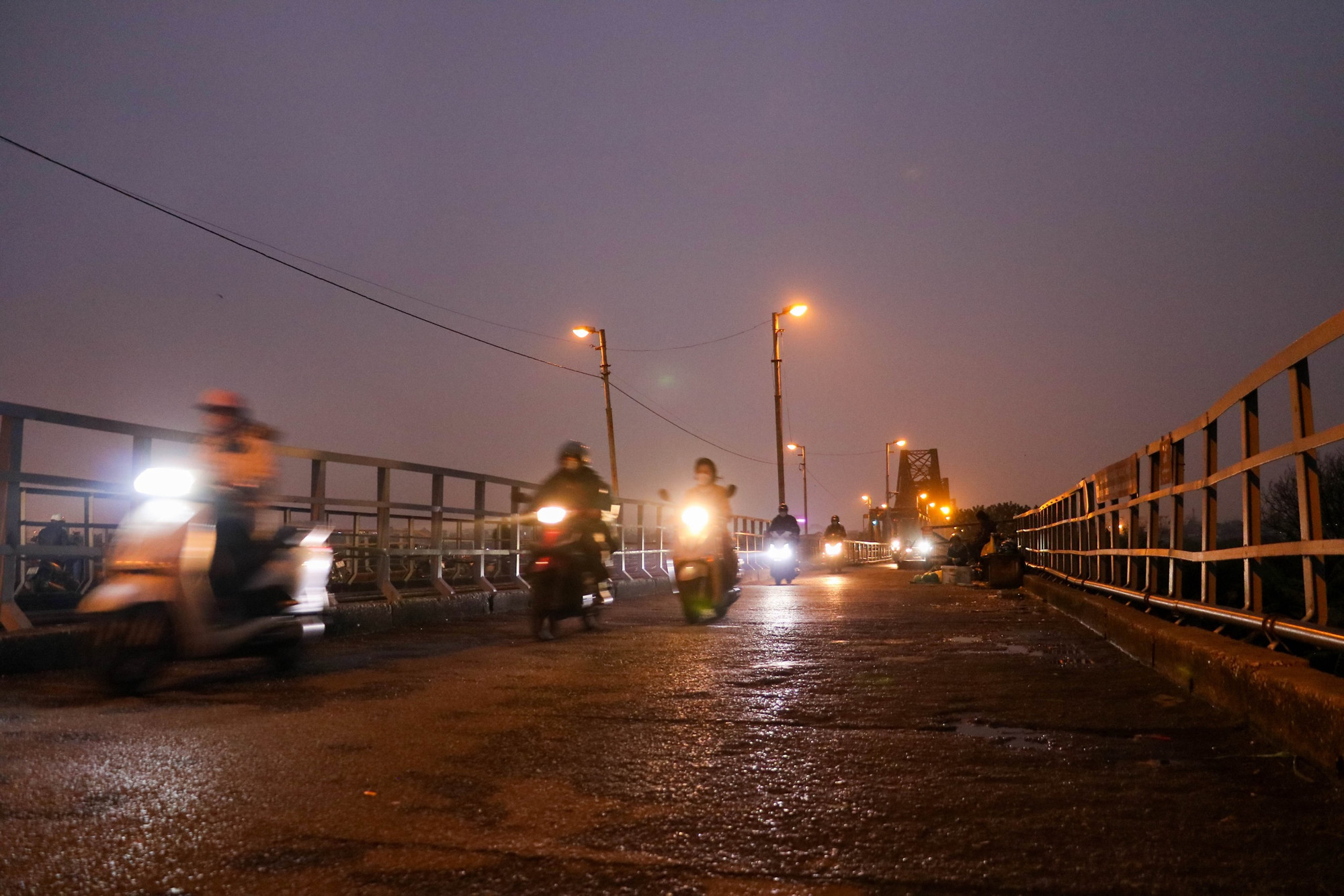 Khu vực cầu Long Biên lúc chập choạng tối người dân phải bật đèn pha khi tham gia giao thông vì tầm nhìn bị giảm sút do sương bụi.