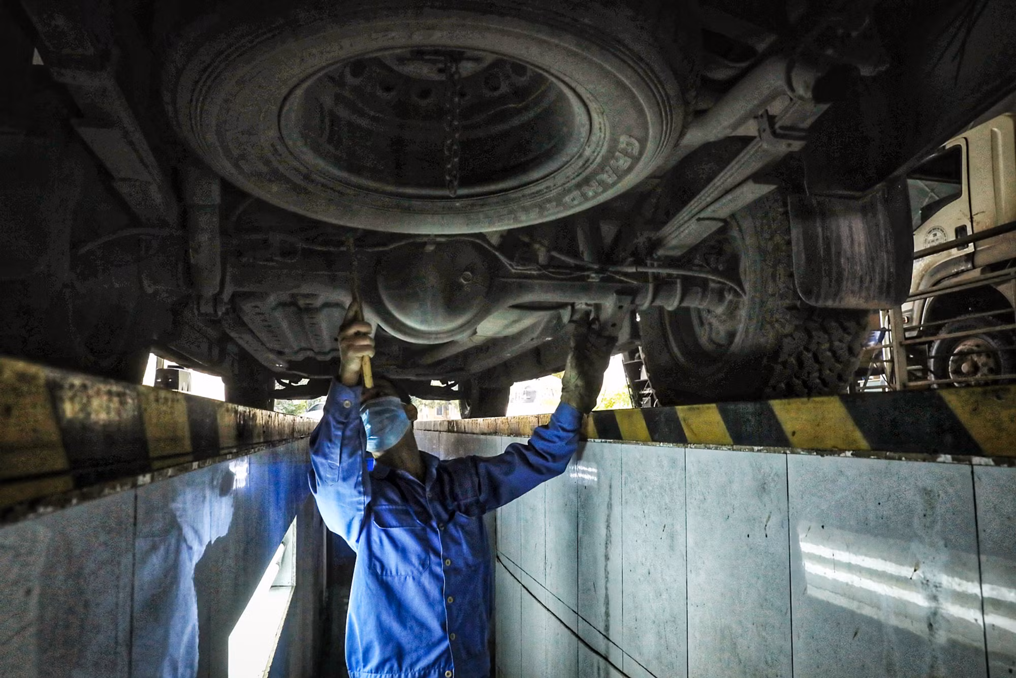 Kiểm định viên kiểm tra gầm bệ phương tiện giao thông.
