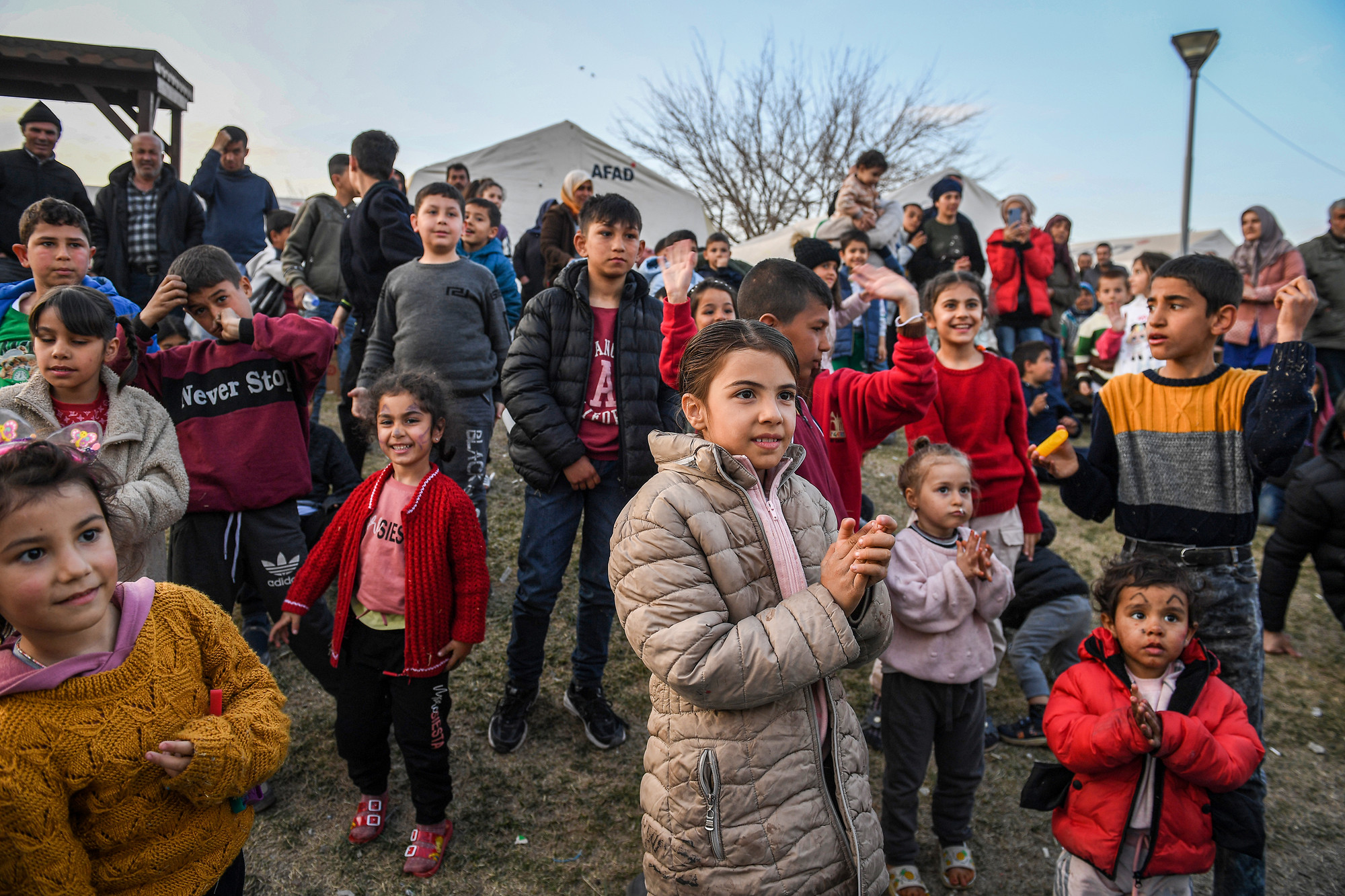 Lũ trẻ phía dưới cũng đồng thanh hô theo. Những tiếng cười khúc khích vang lên ngay bên những công trình đổ nát.