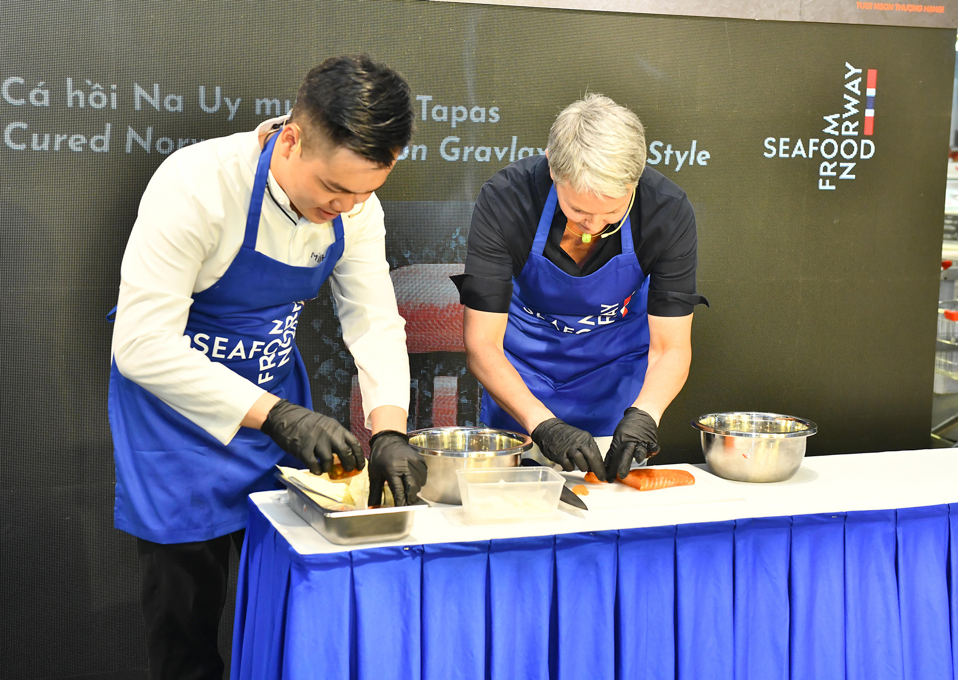 Đại sứ Na Uy Hilde Solbakken cùng đầu bếp chuẩn bị, chế biến món cá hồi Na Uy muối. Đại sứ Na Uy Hilde Solbakken cùng đầu bếp chuẩn bị, chế biến món cá hồi Na Uy muối.