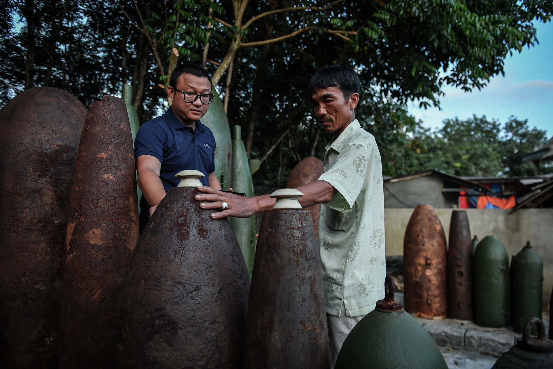 "Khoảng 20 năm trước, gần như hộ gia đình nào ở Hải Thái cũng đi tìm bom, mìn. Chúng tôi sẽ cưa chúng ra, tháo lấy thuốc nổ, kim loại quý để bán. Ngày ấy, nếu không làm thế cũng chẳng biết lấy gì sinh sống", anh Hoàng kể lại. Chung quanh vẫn chất đầy những vỏ bom đủ loại kích cỡ.