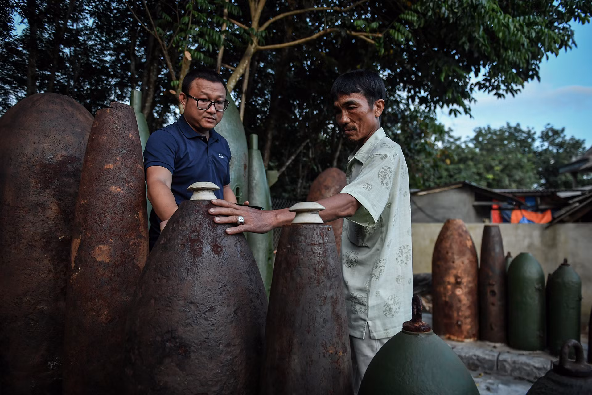 "Khoảng 20 năm trước, gần như hộ gia đình nào ở Hải Thái cũng đi tìm bom, mìn. Chúng tôi sẽ cưa chúng ra, tháo lấy thuốc nổ, kim loại quý để bán. Ngày ấy, nếu không làm thế cũng chẳng biết lấy gì sinh sống", anh Hoàng kể lại. Chung quanh vẫn chất đầy những vỏ bom đủ loại kích cỡ.