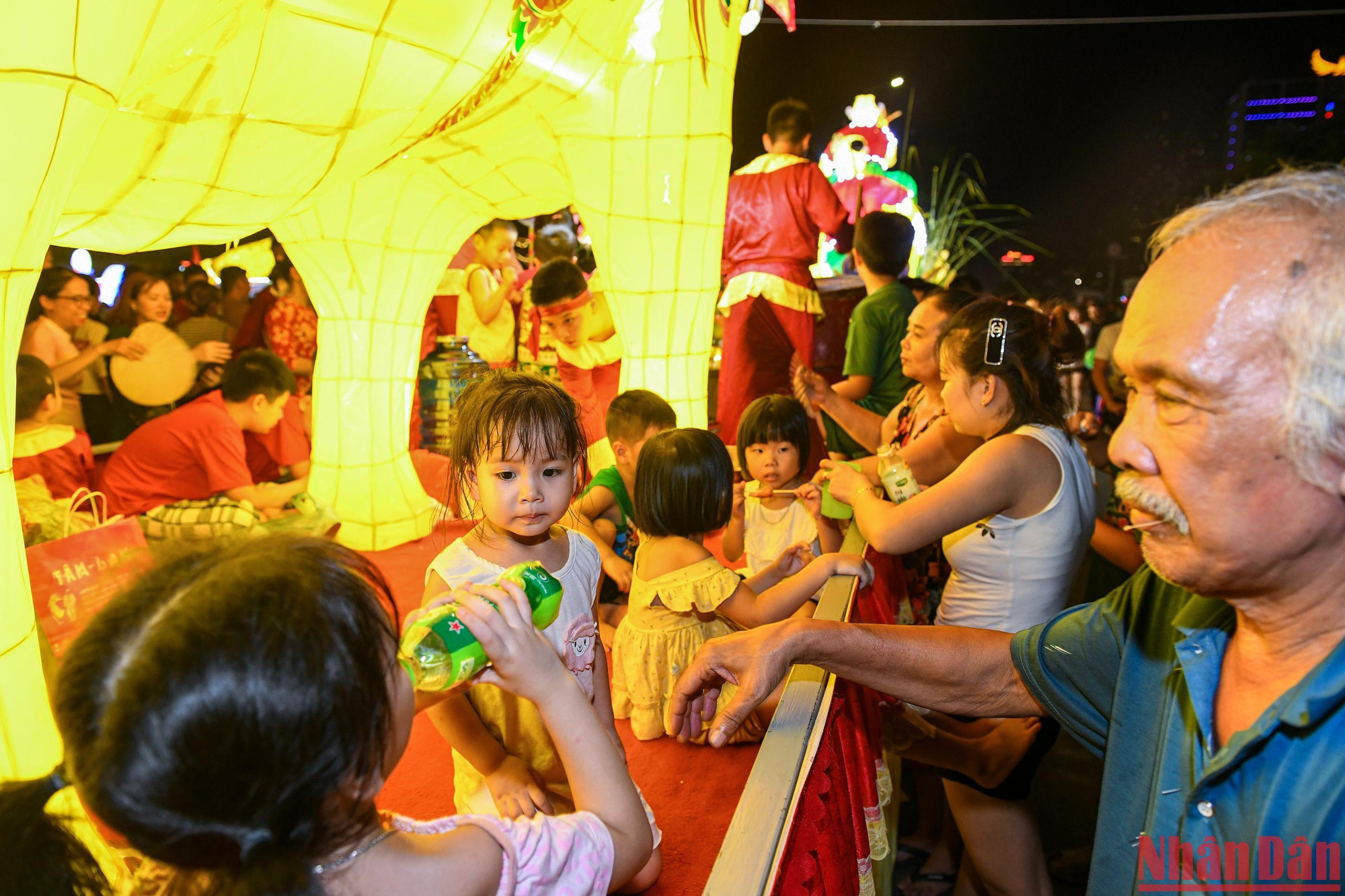 Các em bé ngồi trên xe mô hình được ông bà, bố mẹ chăm sóc, tiếp nước trong quá trình diễu hành vài tiếng đồng hồ.