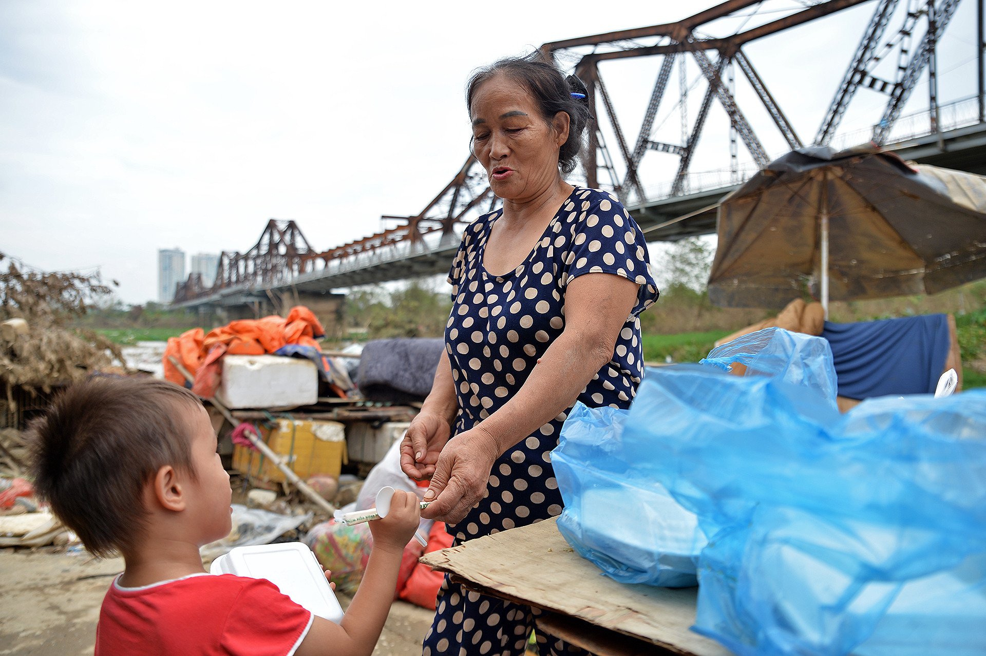 "Phần cơm của con đây", bà Phạm Thị Lĩnh (trong ảnh) phát cơm, mỉm cười thật tươi với cậu bé hàng xóm. Nhưng ngay khi cậu vừa quay đi, bà lại vội lau nhanh những giọt nước mắt chỉ chực trào ra. "Khổ quá đi mất, sách vở, đồ dùng học tập hỏng hết rồi, biết lấy gì mà đến lớp", bà Lĩnh nghẹn ngào nói. "Phần cơm của con đây", bà Phạm Thị Lĩnh (trong ảnh) phát cơm, mỉm cười thật tươi với cậu bé hàng xóm. Nhưng ngay khi cậu vừa quay đi, bà lại vội lau nhanh những giọt nước mắt chỉ chực trào ra. "Khổ quá đi mất, sách vở, đồ dùng học tập hỏng hết rồi, biết lấy gì mà đến lớp", bà Lĩnh nghẹn ngào nói.