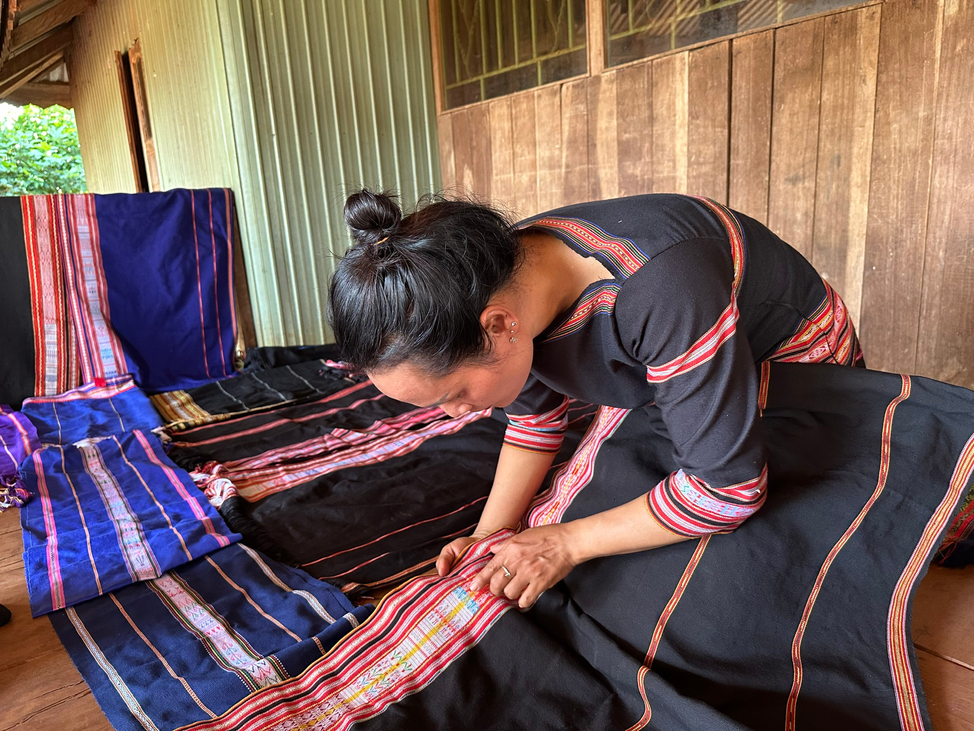 Chị H’Uyên Niê kiểm tra các họa tiết trên tấm vải thổ cẩm. (Ảnh THI PHONG)