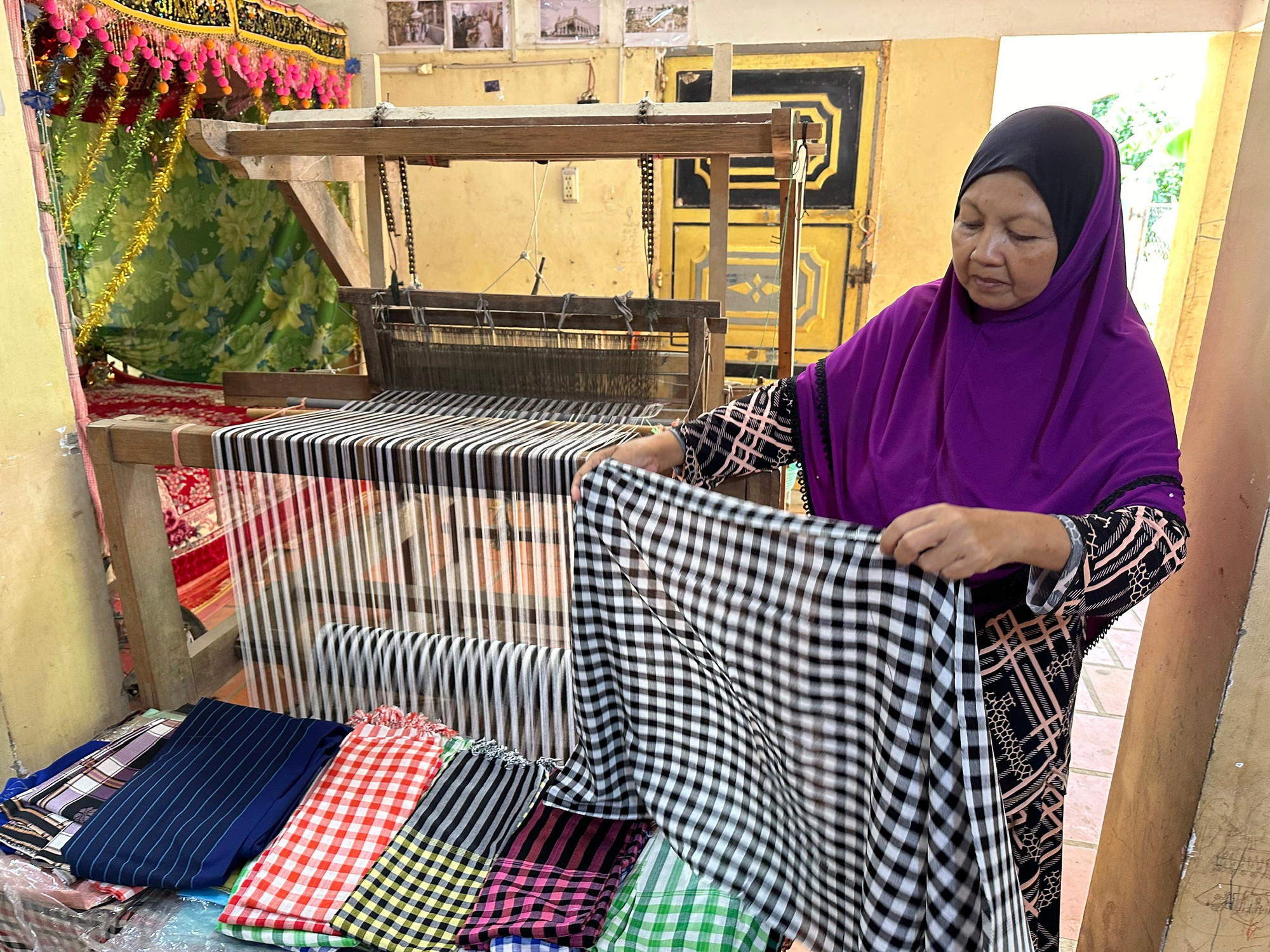 Chị chị Romah giới thiệu sản phẩm khăn kẻ caro do cơ sở của chị sản xuất. (Ảnh: Thi Phong)