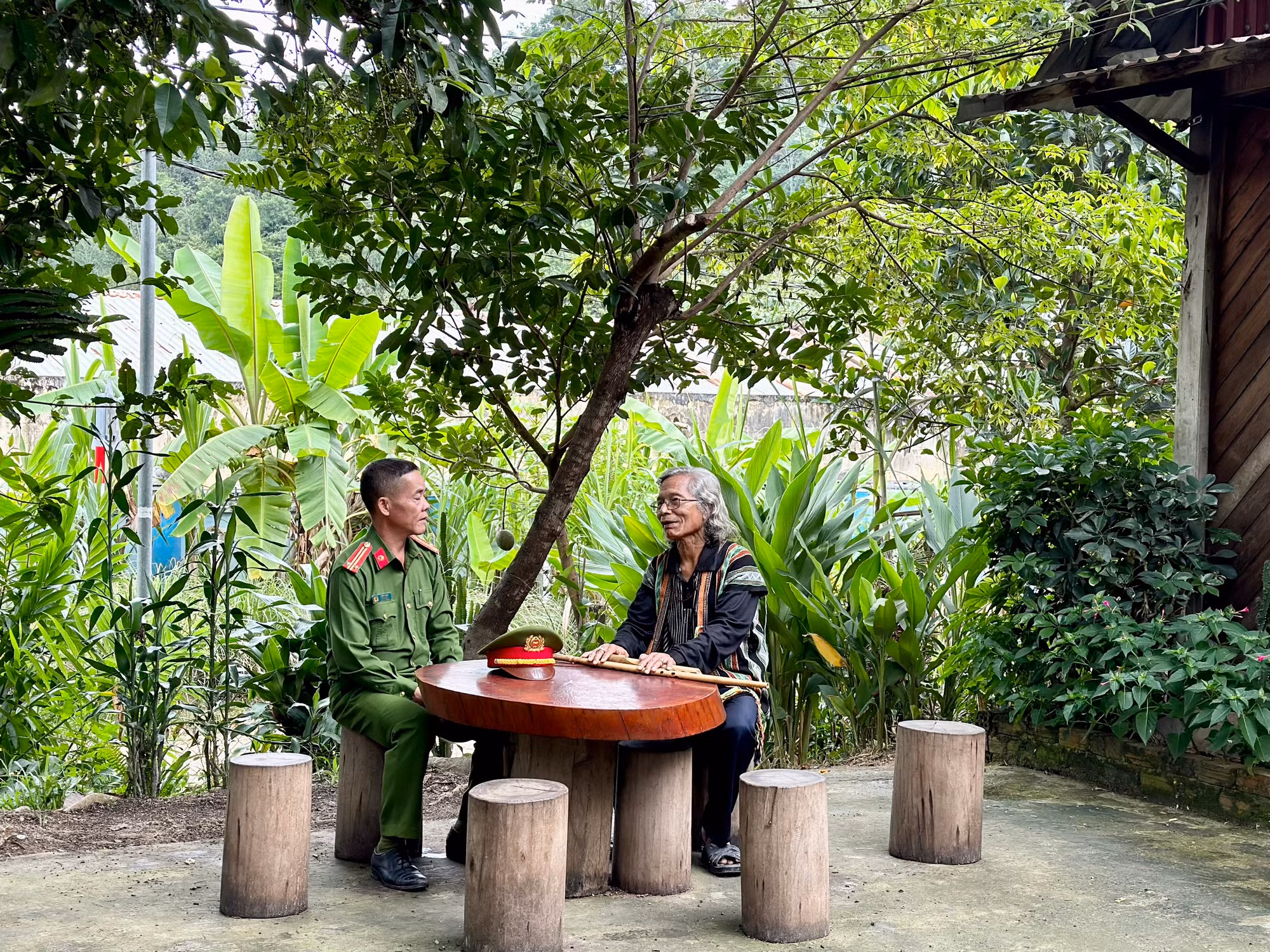 Trung tá Ating Chơn trao đổi với già làng Bríu Pố về công tác giữ gìn an ninh trật tự tại địa phương
