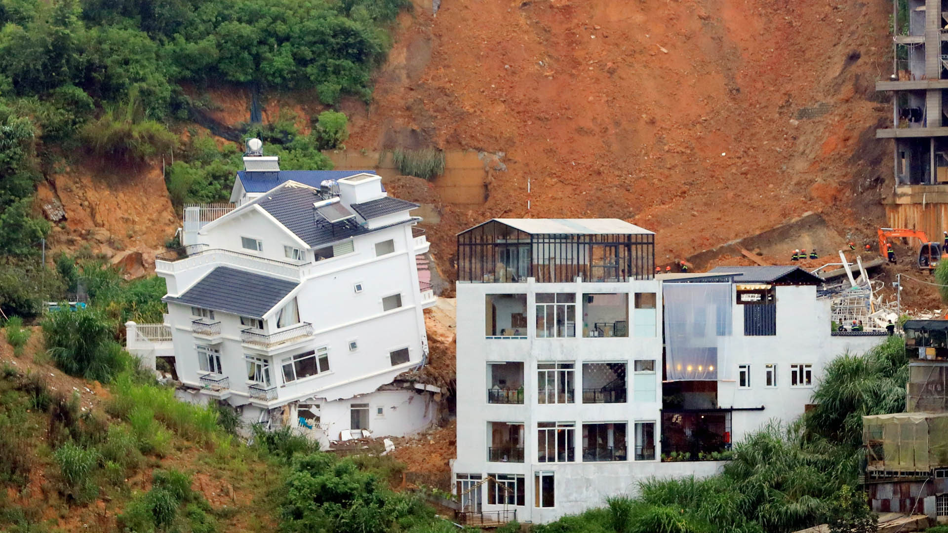 Trong ngôi nhà bị xô lệch (bên trái), lúc vụ sạt lở xảy ra có 5 người đang ở.