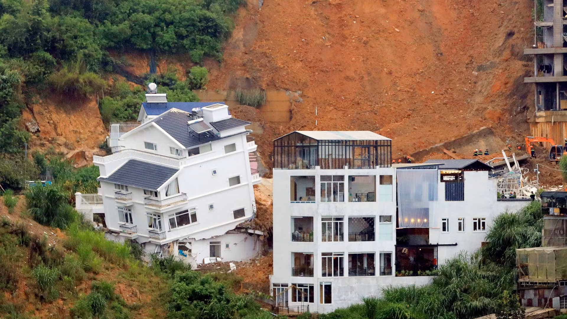 Trong ngôi nhà bị xô lệch (bên trái), lúc vụ sạt lở xảy ra có 5 người đang ở.