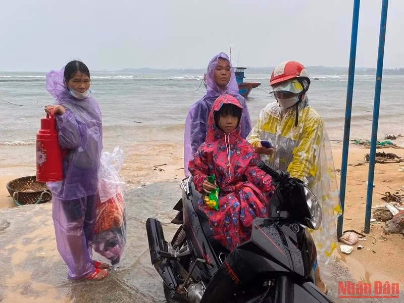 Chị em bà Lê Thị Vân cùng con cái mang vật dụng cá nhân di chuyển lên khu trú tạm của Trường Tiểu học Bình Hải. (Ảnh: ĐÔNG HUYỀN)