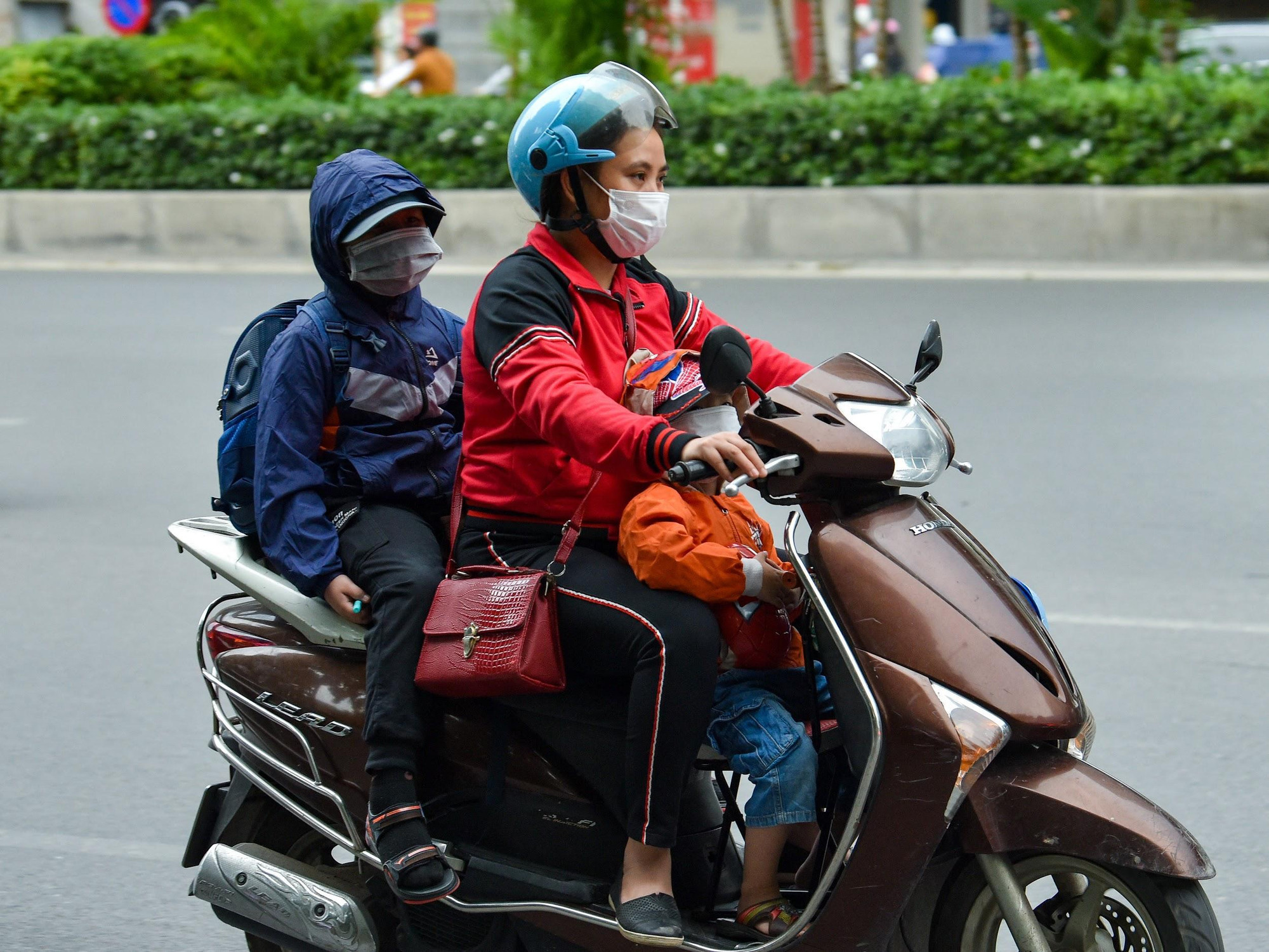 Hình ảnh phụ huynh đưa con nhỏ đi học trong thời tiết se lạnh buổi sáng sớm.