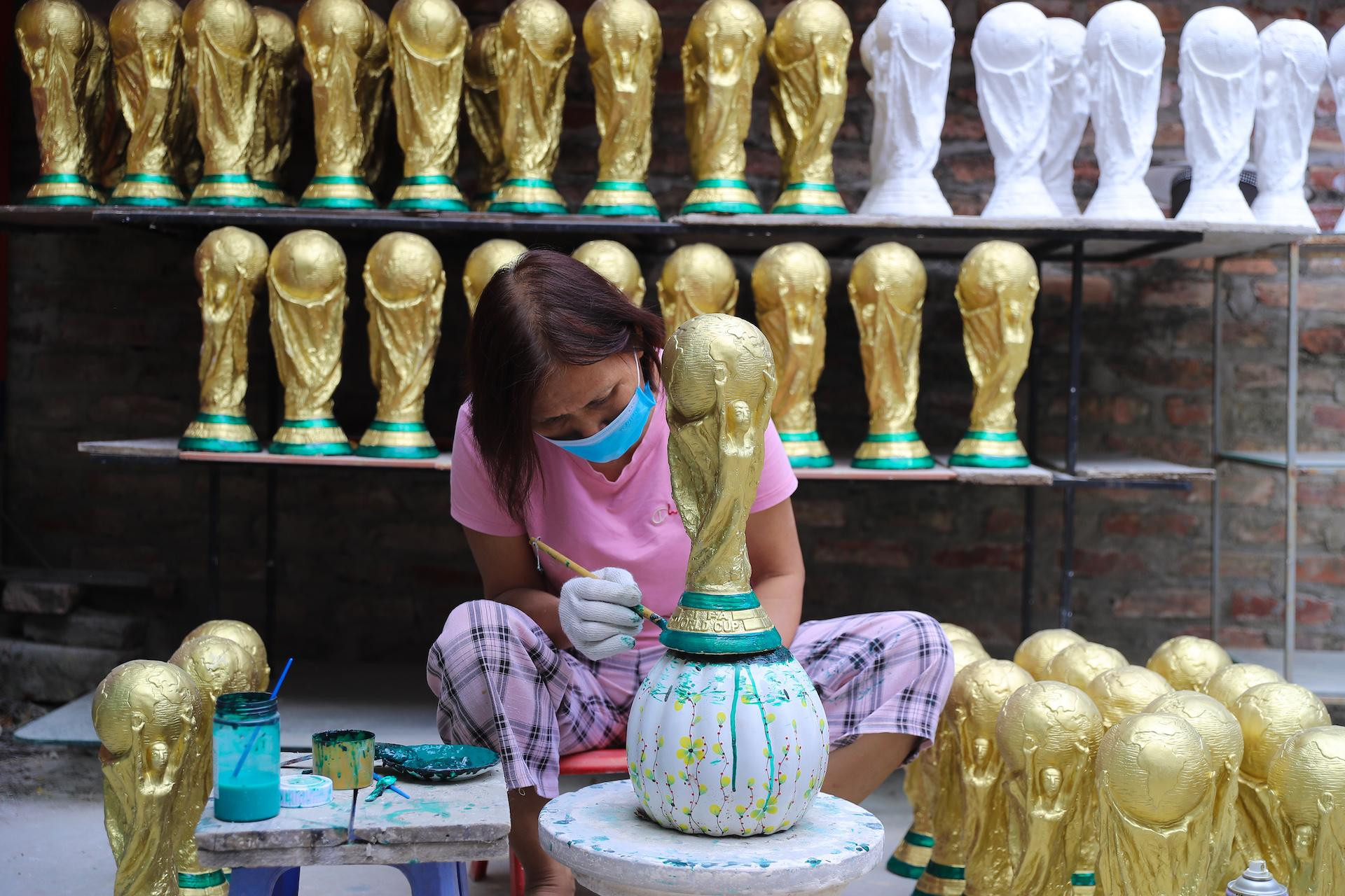 Người thợ đang hoàn thiện phần đế của chiếc cúp vàng World Cup 2022 với một lớp sơn màu xanh lá cây. Với bàn tay khéo léo của người Bát Tràng, những chiếc cúp vàng World Cup phiên bản Việt Nam được ra đời.
