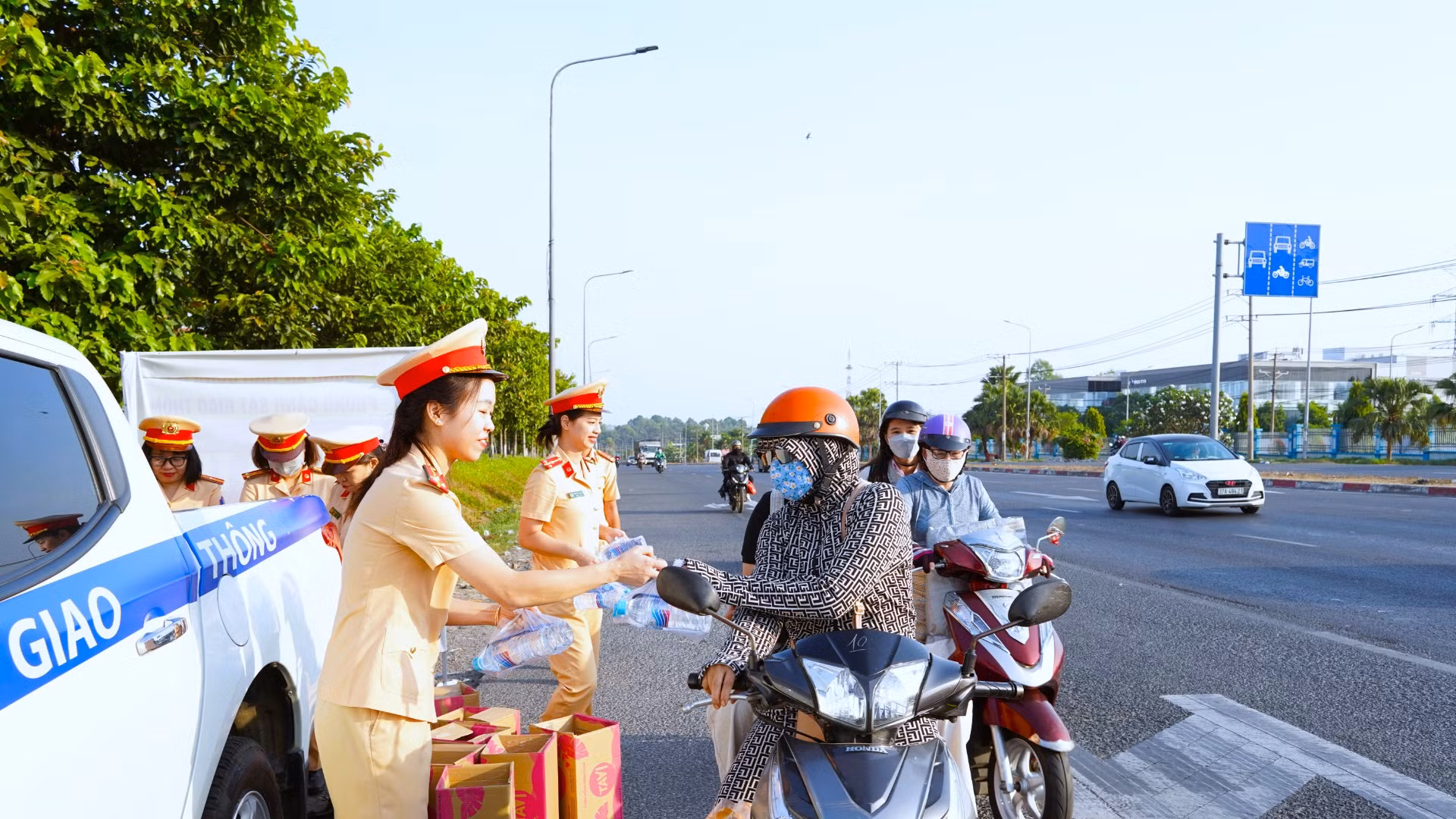 Nữ cảnh sát giao thông Công an tỉnh Đồng Nai phát nước suối, khăn lạnh cho người đi xe máy trên Quốc lộ 1A, đoạn qua địa bàn thành phố Biên Hòa.