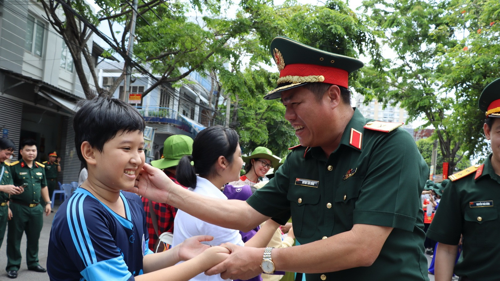 Một em bé cùng người dân ra đường chào đón lực lượng diễu binh, diễu hành.