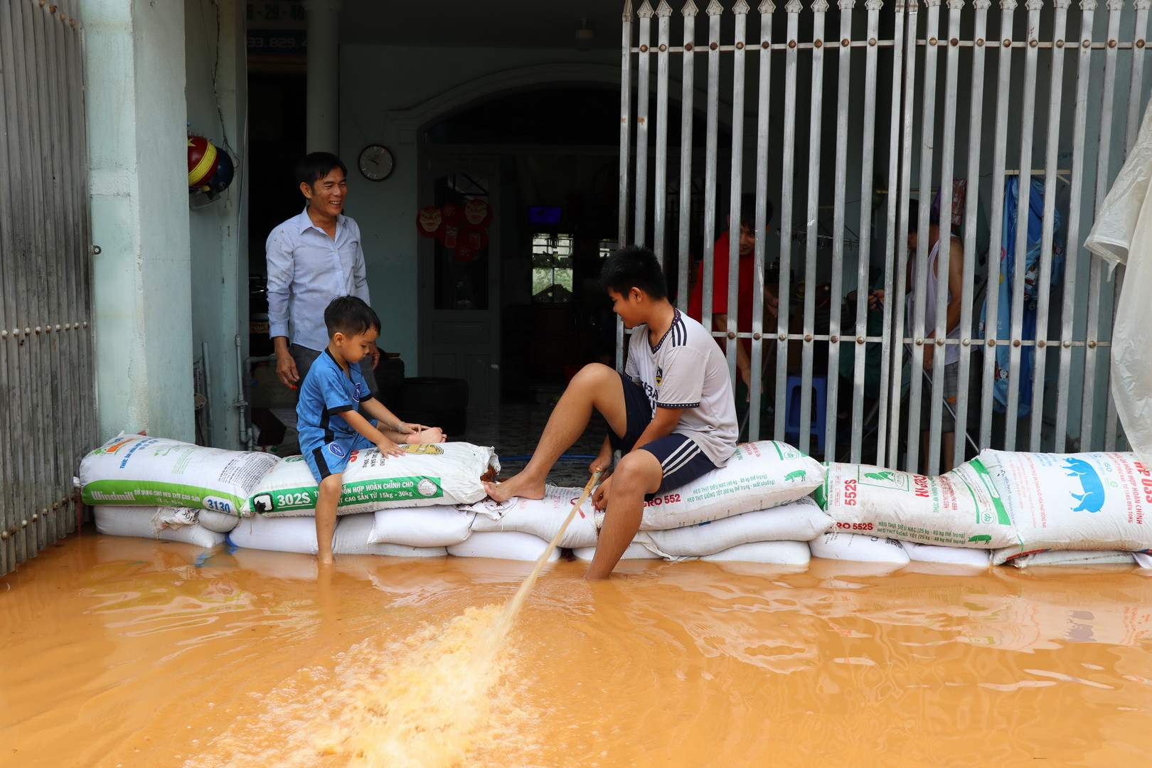Một hộ dân dùng các bao cát chặn dòng nước tràn vào nhà; đồng thời bơm số nước lũ trong nhà ra bên ngoài.