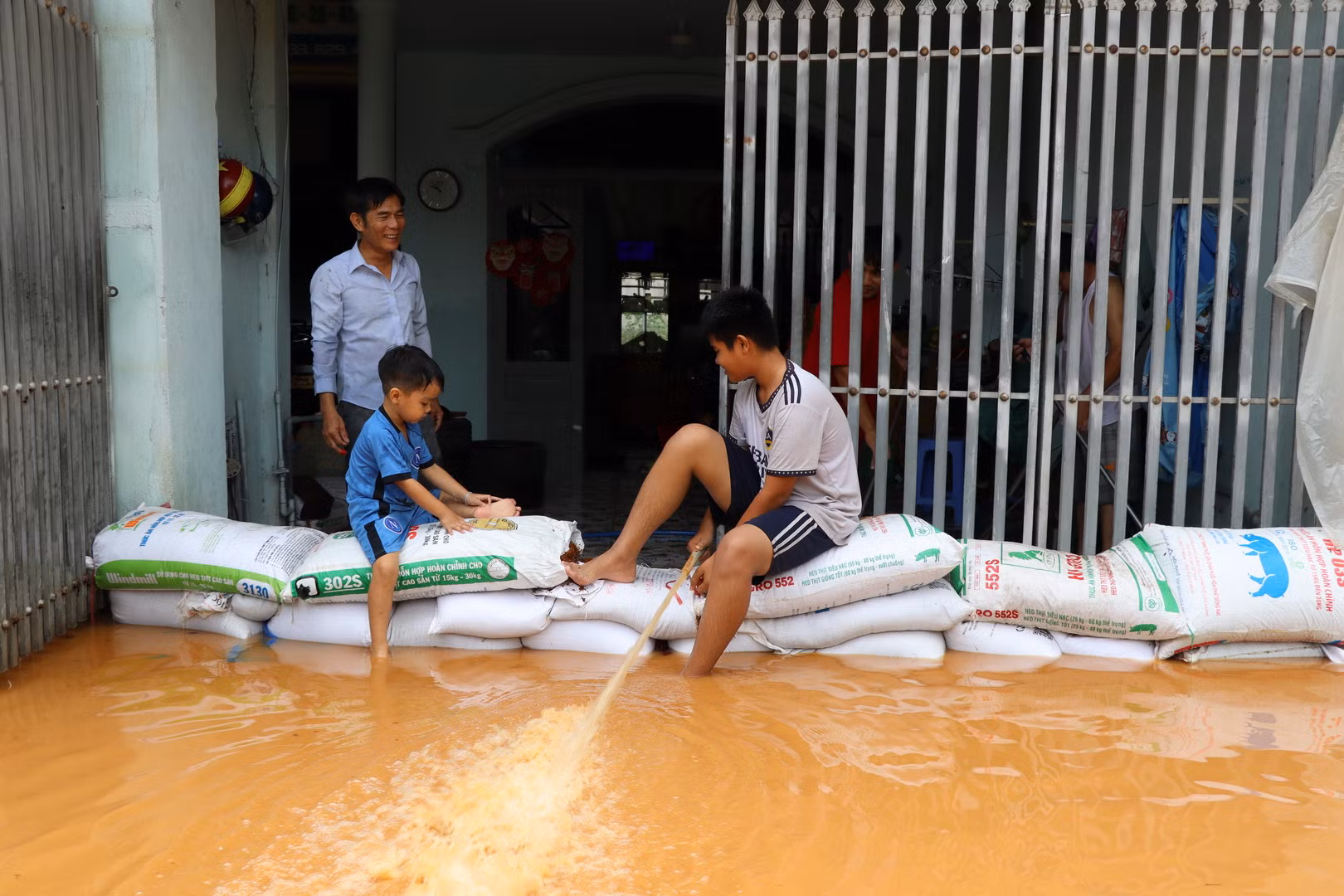 Một hộ dân dùng các bao cát chặn dòng nước tràn vào nhà; đồng thời bơm số nước lũ trong nhà ra bên ngoài.