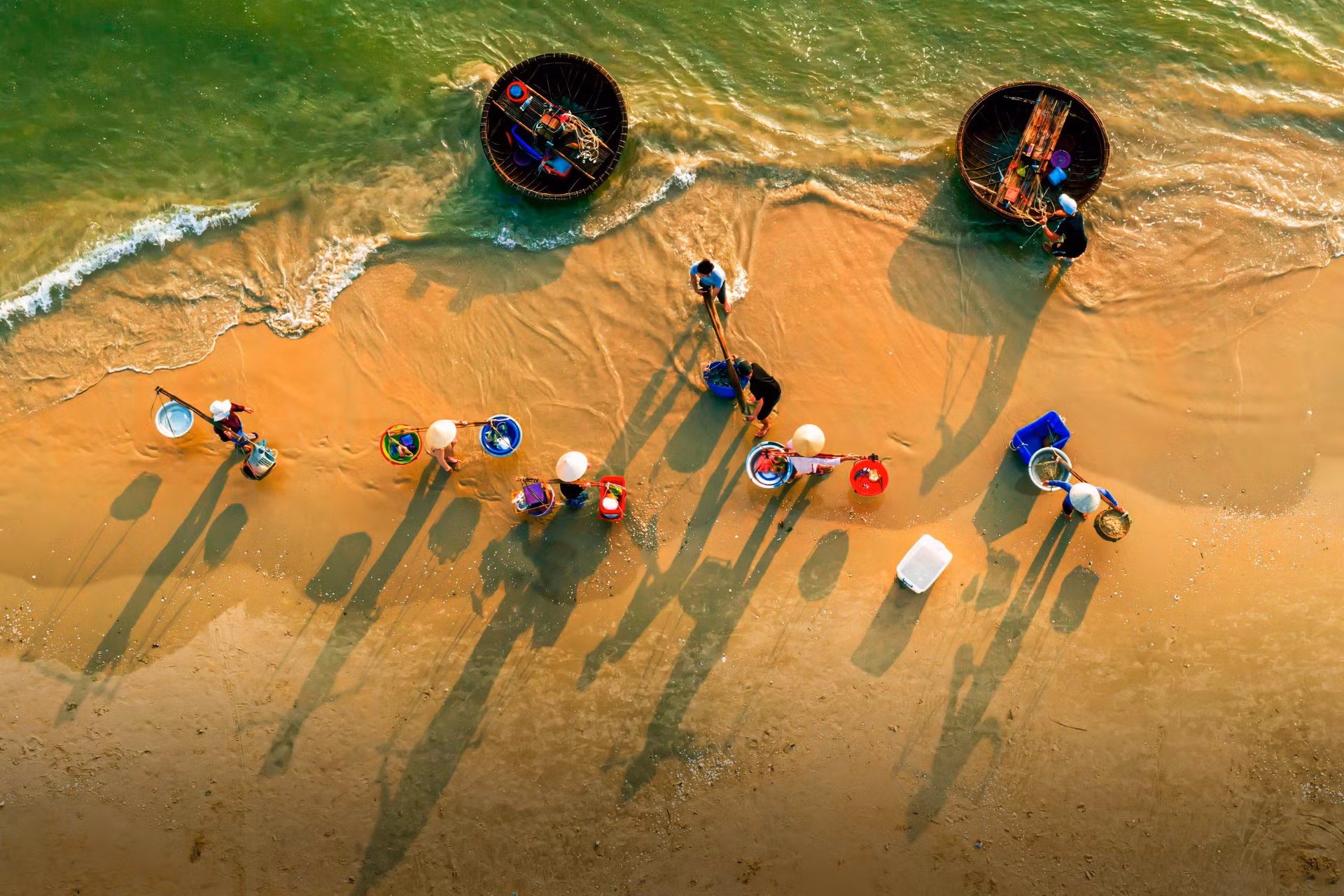 Sau khi các thúng của ngư dân đánh bắt gần bờ trở về, những người phụ nữ làng chài gánh hải sản mang đi tiêu thụ.