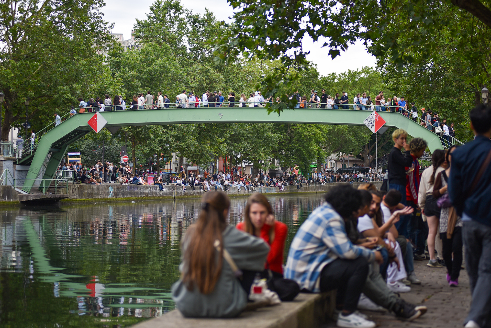 Olympic Paris 2024 đánh dấu sự trở lại của Thế vận hội mùa hè tại nước Pháp sau 100 năm tính từ lần đăng cai tổ chức trước đó. Do vậy, dọc theo bờ kè Jemmapes, người dân sinh sống tại quận 10 và du khách trong khu vực đã tập trung đông đủ để cùng nhau đón ngọn đuốc. (Ảnh: MINH DUY)