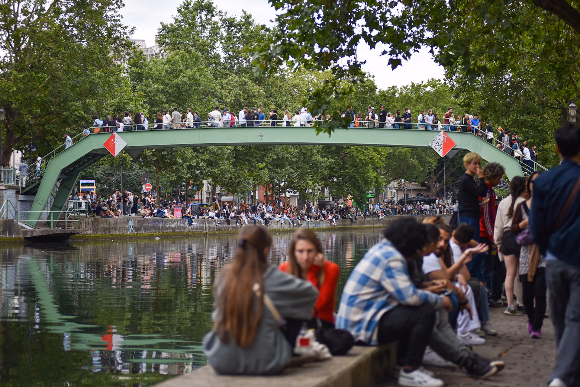 Olympic Paris 2024 đánh dấu sự trở lại của Thế vận hội mùa hè tại nước Pháp sau 100 năm tính từ lần đăng cai tổ chức trước đó. Do vậy, dọc theo bờ kè Jemmapes, người dân sinh sống tại quận 10 và du khách trong khu vực đã tập trung đông đủ để cùng nhau đón ngọn đuốc. (Ảnh: MINH DUY)