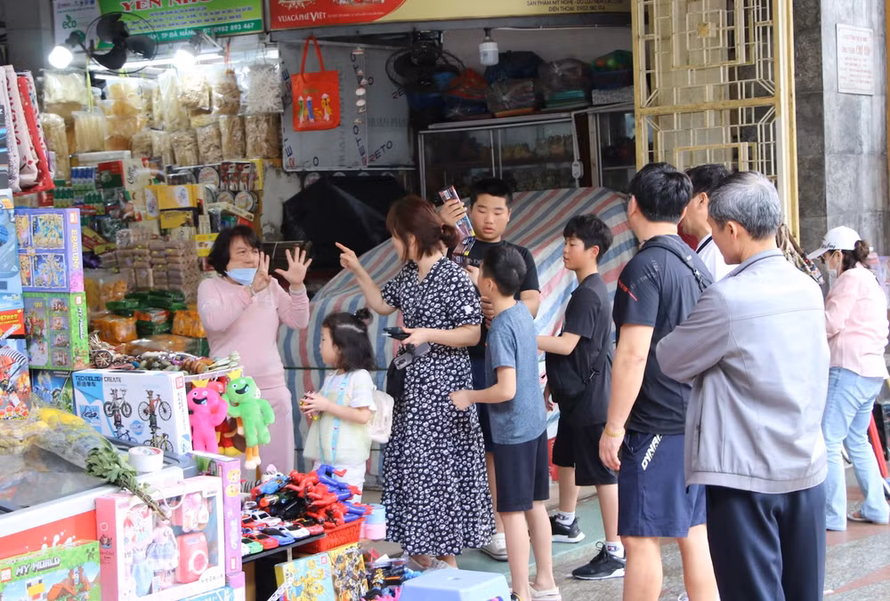 Khách du lịch và tiểu thương trao đổi giá cả.
