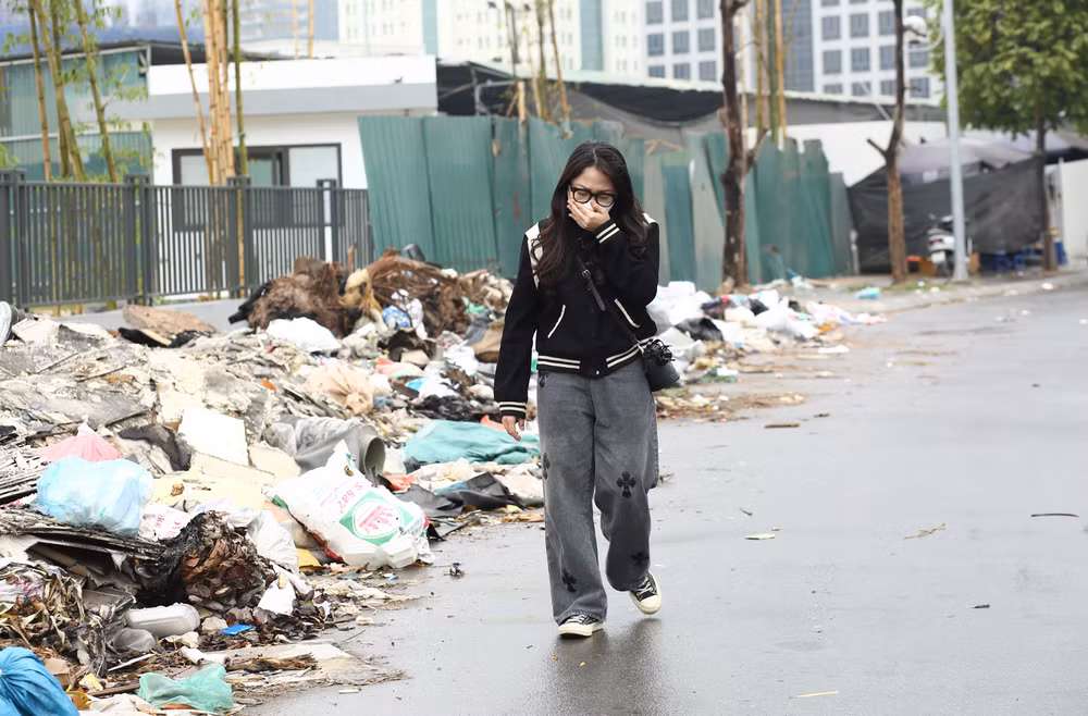Người đi đường thấy khó chịu với mùi hôi thối từ bãi rác. (Ảnh: Thu Phương)