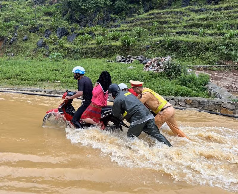 Cảnh sát giao thông Hà Giang lội nước đẩy xe máy, đưa người dân qua điểm ngập an toàn.