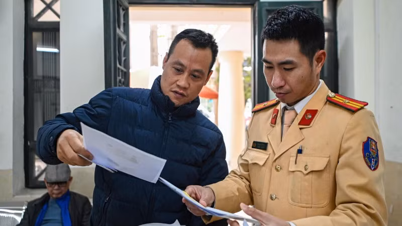 Lực lượng chức năng hướng dẫn người dân các thủ tục kê khai hồ sơ cấp đổi giấy phép lái xe.