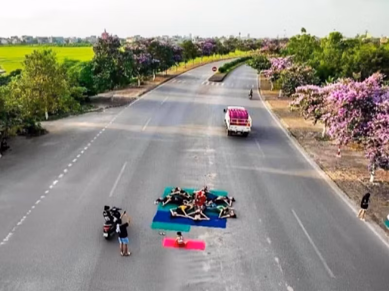 Nhóm phụ nữ mặc đồ thể dục nằm, ngồi trên đường chụp ảnh.