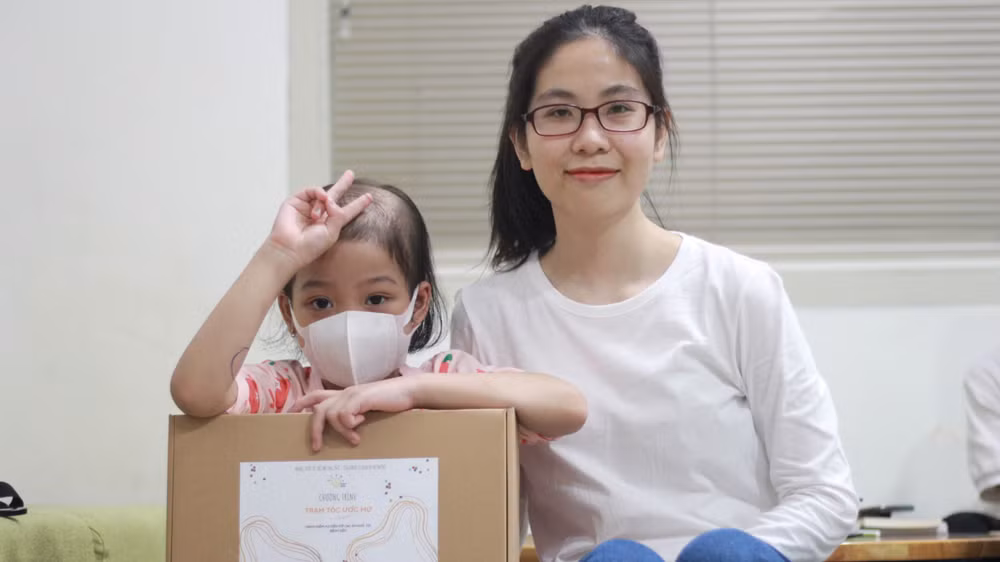 Diệu Thuần và một bé gái nhận được bộ tóc mới. 