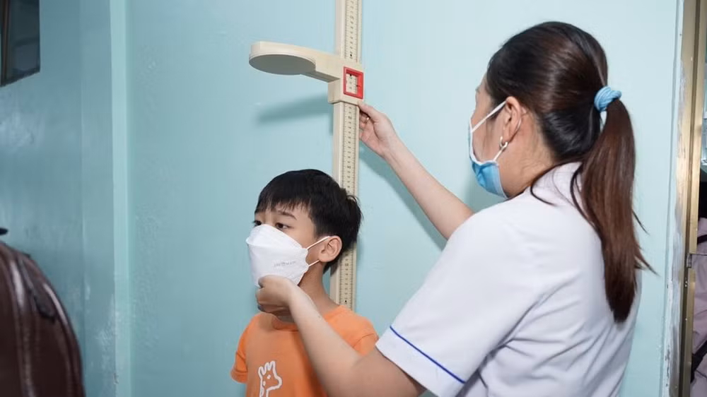 Nhân viên y tế đo chiều cao cho trẻ khi tham gia tầm soát.
