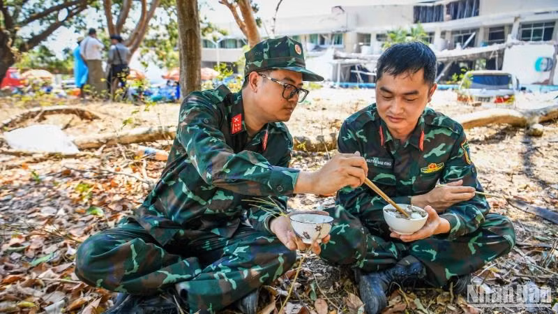 Lực lượng cứu nạn, cứu hộ Quân đội nhân dân Việt Nam tranh thủ ăn cơm để chuẩn bị vào ca làm việc buổi chiều. (Ảnh: THÀNH ĐẠT)