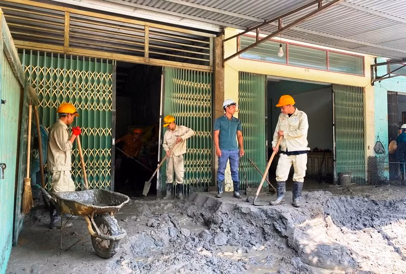 Công nhân Nhà máy tuyển đồng Tả Phời giúp người dân khắc phục hậu quả do sự cố vỡ cống xả tràn hồ thải nhà máy gây ra. (Ảnh: QUỐC HỒNG)