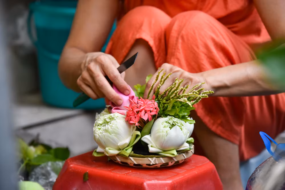 Một người bán đang cẩn thận, tỉ mẩn làm đồ trang trí mâm cho khách.