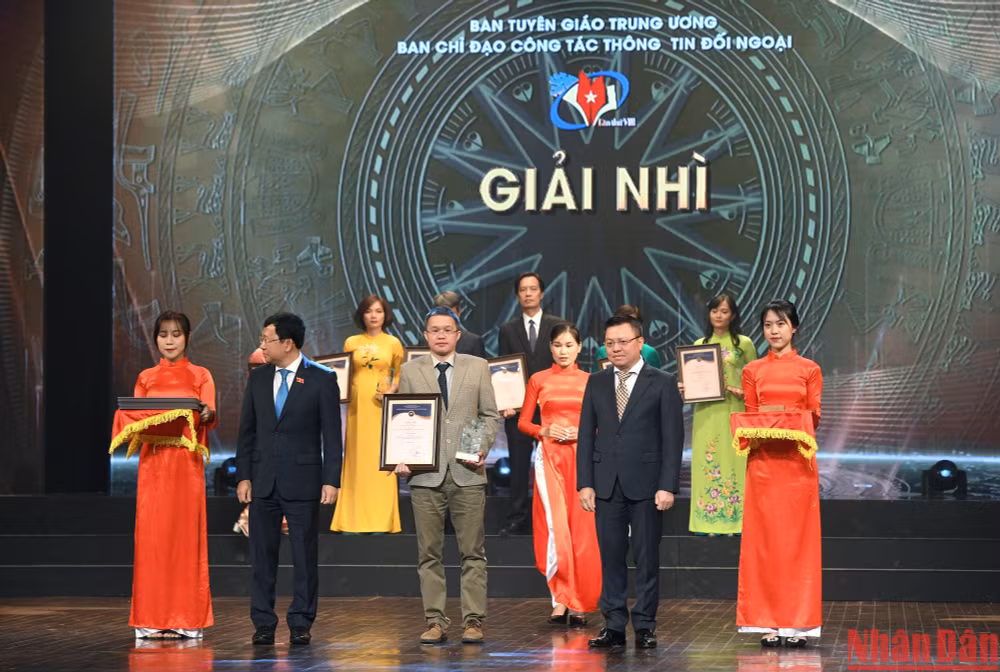 Tổng Biên tập Báo Nhân Dân, Chủ tịch Hội Nhà báo Việt Nam Lê Quốc Minh và Chủ nhiệm Ủy ban Đối ngoại của Quốc hội Vũ Hải Hà trao giải Nhì cho đại diện các nhóm tác giả đạt giải. (Ảnh: Thành Đạt)
