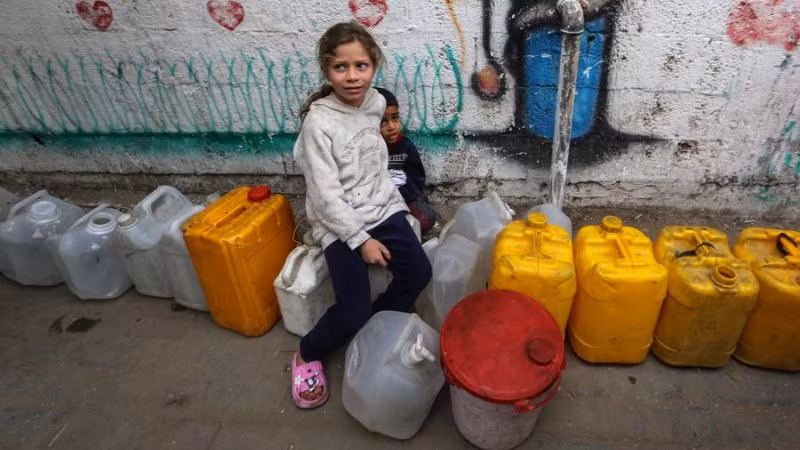 Trẻ em Palestine chờ lấy nước bên trong một trại di tản ở Gaza, ngày 6/4/2025. (Ảnh: Xinhua) 