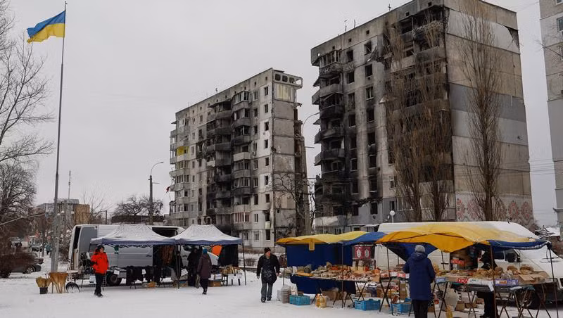 Người dân Ukraine mua thực phẩm tại một khu chợ đường phố phía trước tòa nhà chung cư bị hư hại tại thị trấn Borodianka, tỉnh Kiev, Ukraine, ngày 15/12/2022. (Ảnh: Reuters)