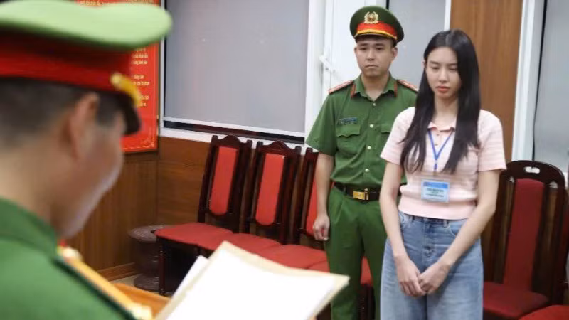 Hoa hậu Nguyễn Thúc Thùy Tiên nghe đọc lệnh từ cơ quan công an. (Ảnh: Bộ Công an) 