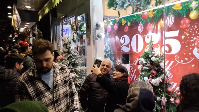 Người dân chụp ảnh cạnh cửa hiệu với đồ trang trí chào năm mới 2025 ở Tehran, Iran.