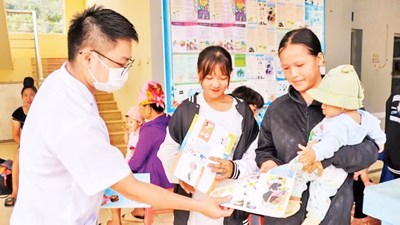 Cán bộ Trạm Y tế xã Mường Cai, huyện Sông Mã, tỉnh Sơn La phát tờ rơi tuyên truyền về công tác dân số cho nhân dân. (Ảnh HUYỀN TRANG)