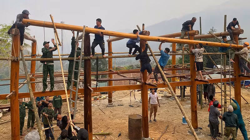 Các lực lượng trợ giúp hộ dân ở khu phố Tén Tằn xây lắp ngôi nhà sàn.