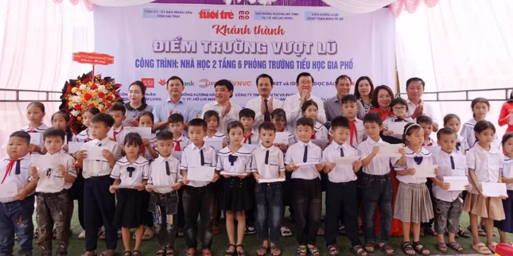 Các đại biểu dự lễ khánh thành điểm trường vượt lũ trao quà cho các em trường tiểu học Gia Phố (Hương Khê).