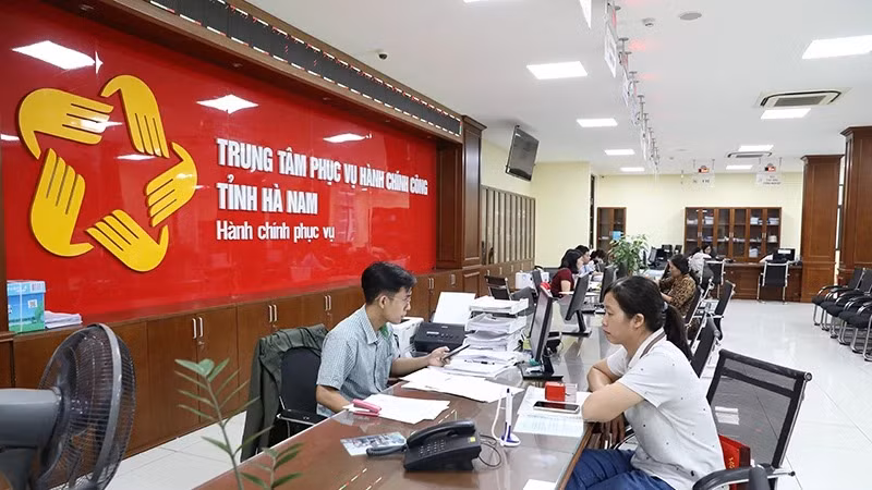 Cán bộ, công chức Trung tâm hành chính công tỉnh Hà Nam giải quyết thủ tục hành chính cho người dân. (Ảnh ĐÀO PHƯƠNG)