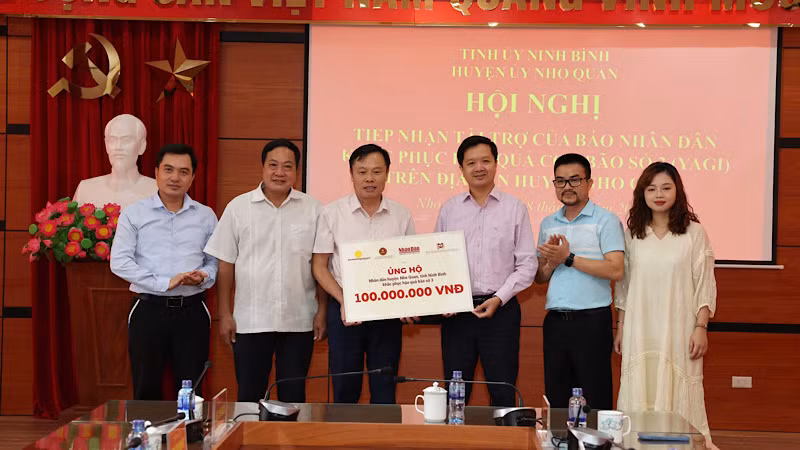 Đại diện Báo Nhân Dân và Công ty cổ phần Văn hóa học và học Việt Nam trao tặng tiền ủng hộ cho huyện Nho Quan (Ninh Bình). 