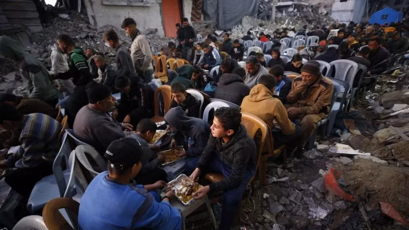 Người dân Palestine ngồi ăn giữa những ngôi nhà bị phá hủy tại thị trấn Jabalia, phía bắc Dải Gaza.