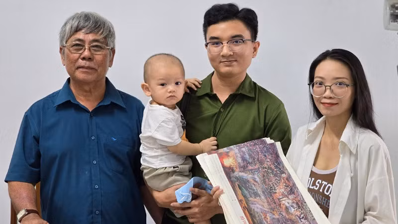 Một gia đình trẻ bế cả con trai 16 tháng tuổi đến nhận tranh panorama Chiến thắng Điện Biên Phủ.