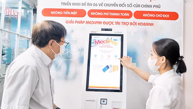 Nhân viên y tế hướng dẫn người dân thực hiện đăng ký khám, chữa bệnh và thanh toán viện phí tại "Kiosk y tế thông minh" Bệnh viện Quận 1. (Ảnh Thế Anh)