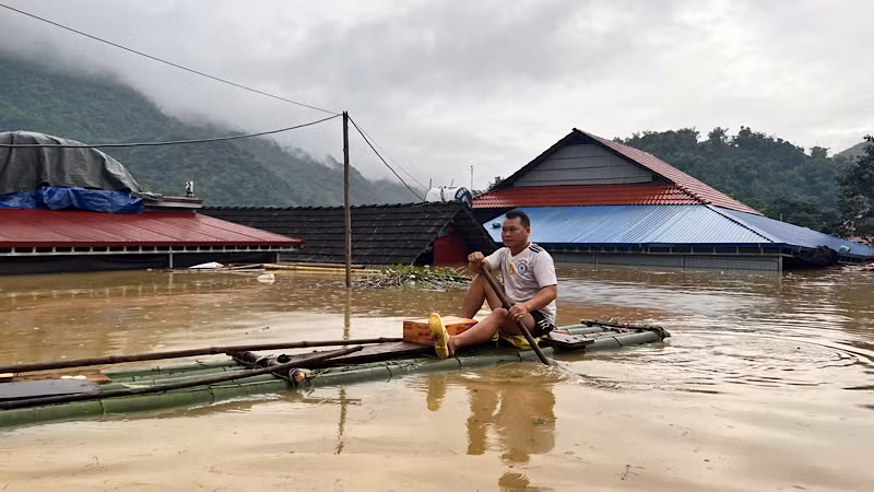 Một hộ dân ở xã Nam Cường, huyện Chợ Đồn di chuyển qua nước ngập bằng bè tre đi nhận nhu yếu phẩm hỗ trợ. (Ảnh: ĐÌNH HỢI).