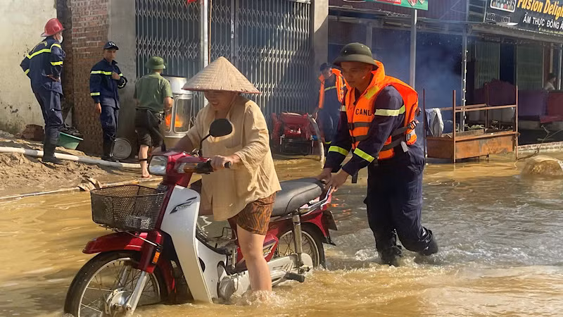 Chiến sĩ công an giúp người dân di chuyển an toàn vùng ngập lụt. (Ảnh: Thùy Dương)